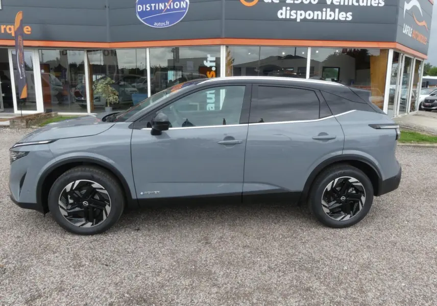 Profil côté gauche du Nissan Qashqai 1.5 e-Power gris métallisé avec toit noir et jantes alliage 18 pouces.