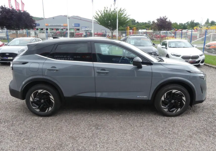 Profil côté gauche du Nissan Qashqai 1.5 e-Power gris métallisé avec jantes alliage noires et toit panoramique noir.