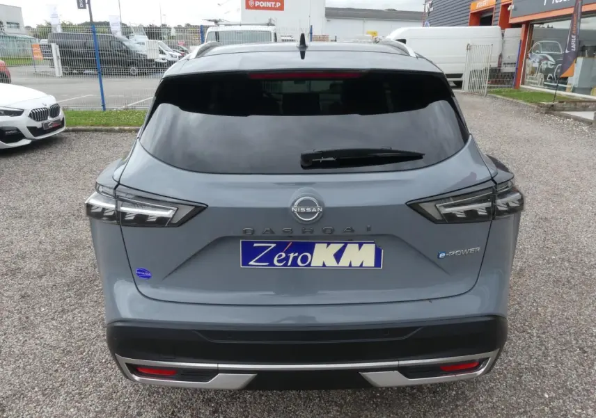 Vue arrière du Nissan Qashqai gris métallisé avec badges e-Power et hayon fermé sur parking.
