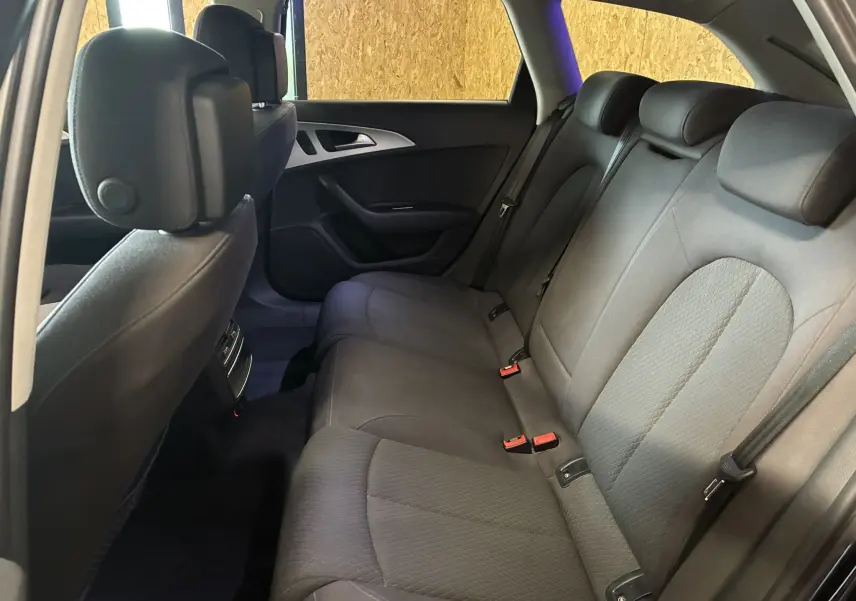 Vue intérieure arrière côté droit de l'Audi A6 Avant 2017, sièges tissu noir avec ceintures et appuie-têtes visibles.