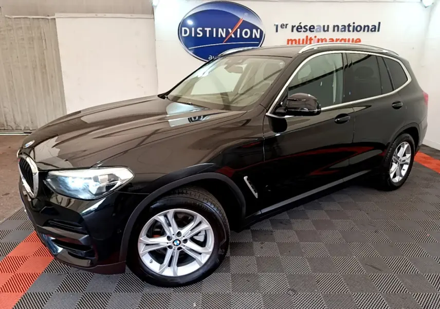BMW X3 xDrive20d noir en 3/4 avant droit, avec jantes alliage et phares LED allumés dans un showroom.