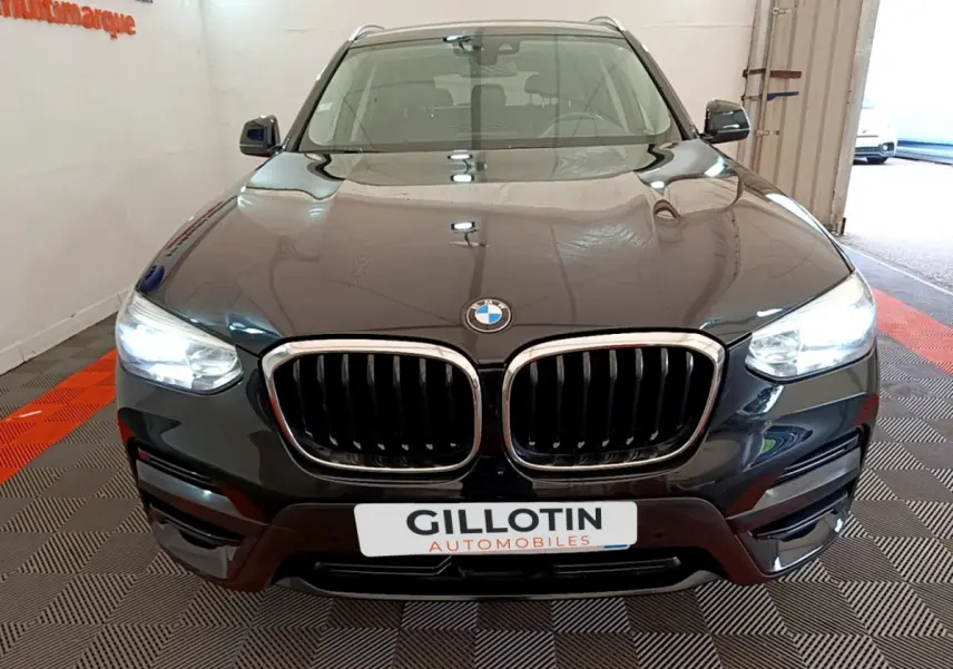 BMW X3 xDrive20d noir vu de face avec calandre double haricot et phares LED allumés dans un showroom.