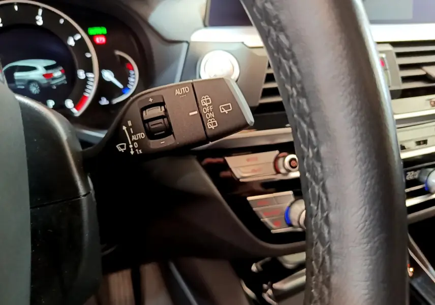 Gros plan sur la manette d’essuie-glace à gauche du volant cuir noir du BMW X3 xDrive20d 2020, tableau de bord en arrière-plan.