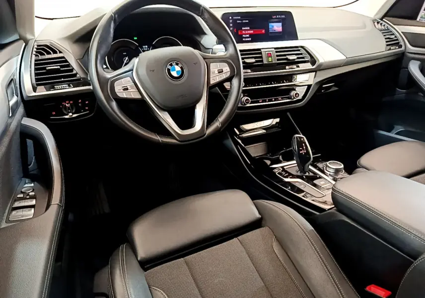 Intérieur noir du BMW X3 xDrive20d 2020 vu côté conducteur, volant cuir multifonctions et écran central 8,8 pouces.