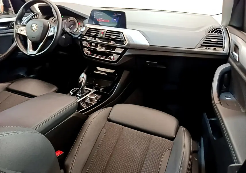 Intérieur noir du BMW X3 xDrive20d 2020, vue côté passager avant sur tableau de bord et console centrale.