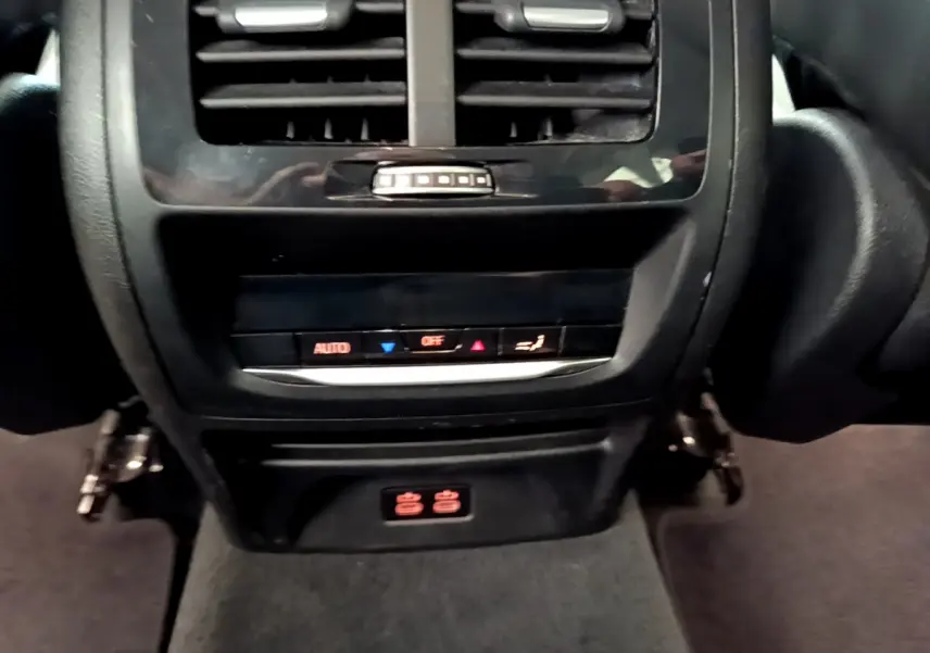 Vue rapprochée de la console arrière noire du BMW X3 xDrive20d 2020 avec commandes climatisation et prises 12V.