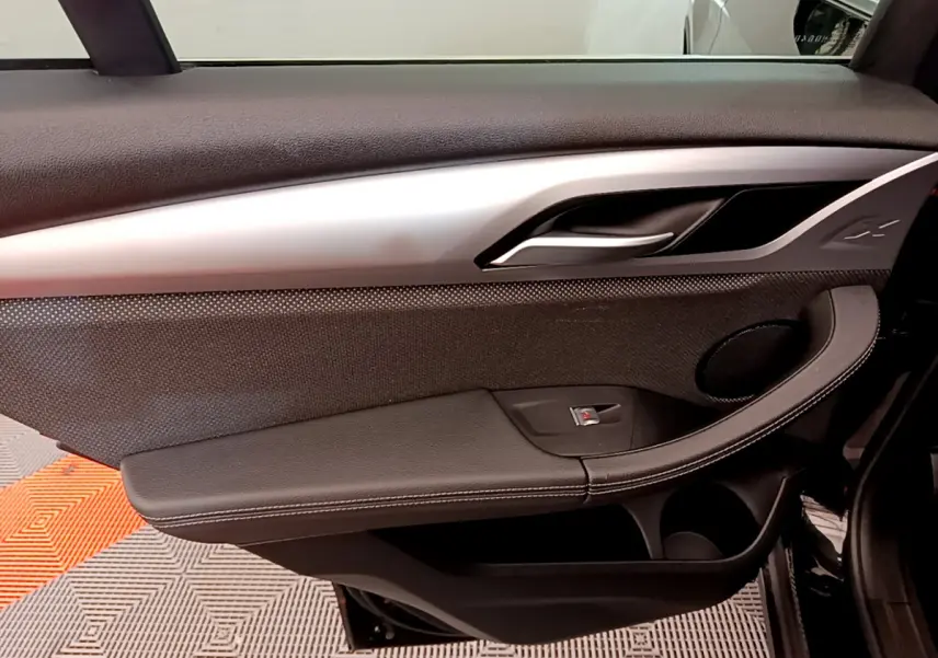 Gros plan sur la porte côté gauche noire du BMW X3 xDrive20d 2020, avec poignée argentée et haut-parleur intégré.
