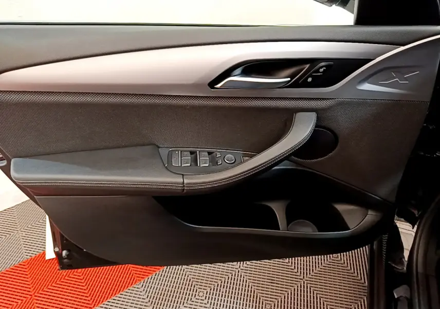 Porte intérieure côté gauche noire du BMW X3 xDrive20d 2020 avec poignée intégrée et commandes électriques des vitres.