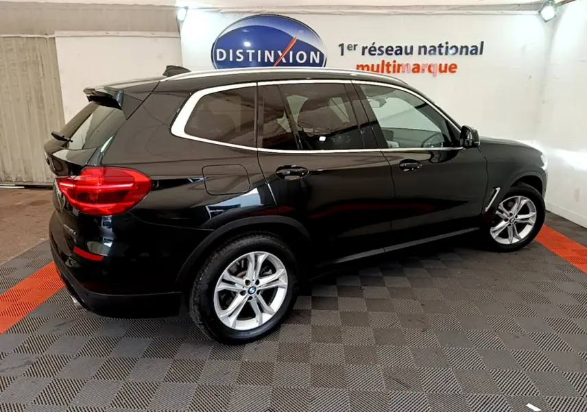 BMW X3 xDrive20d noir vue de profil côté droit dans un showroom avec sol damier gris et rouge