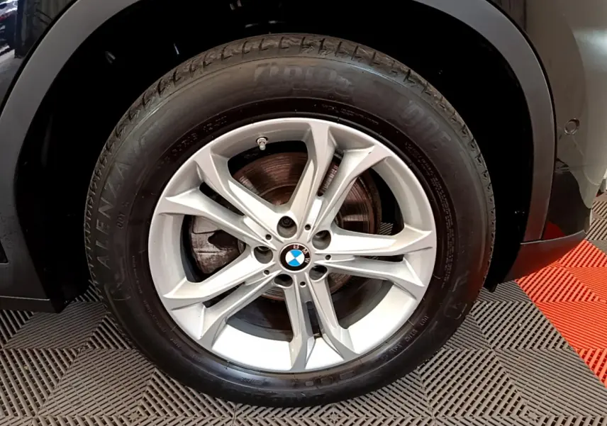 Gros plan sur la roue avant droite du BMW X3 noir 2020, mettant en valeur la jante alliage argentée et le logo BMW central.