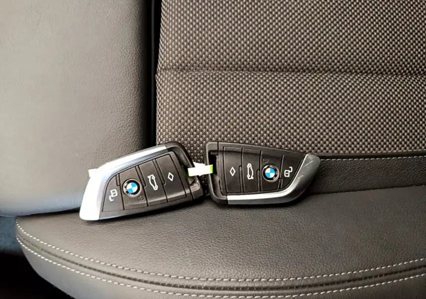 Deux clés BMW posées sur un siège en cuir noir et tissu gris à motifs, intérieur d'un X3 2020 Lounge.