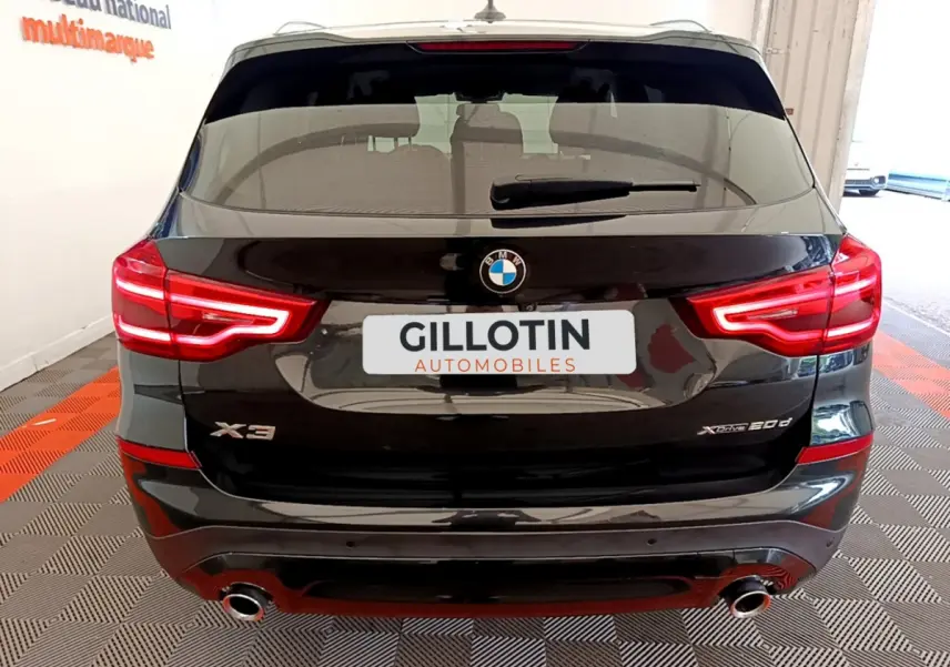 Vue arrière d'un BMW X3 noir xDrive20d avec feux LED allumés et double sortie d'échappement visible.