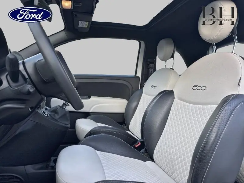 Intérieur de la Fiat 500 2022 en vue latérale, sièges bicolores avec logo 500 brodé et toit panoramique en verre.