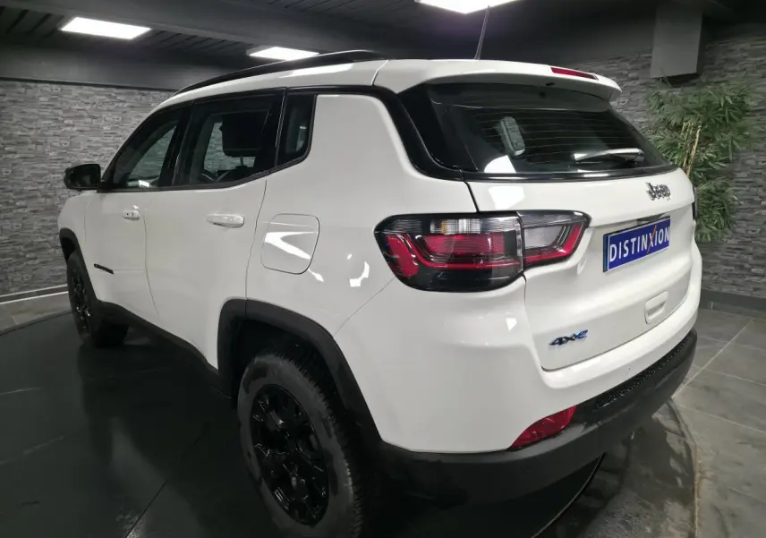 Vue 3/4 arrière droite du Jeep Compass blanc 2024 avec jantes noires et badges 4xe eAWD visibles.