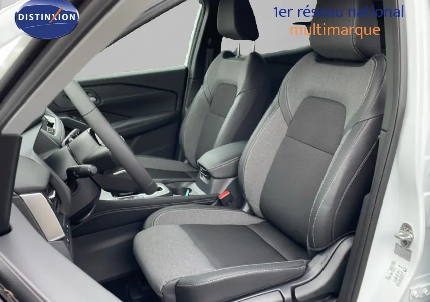 Vue intérieure côté conducteur du Nissan Qashqai blanc nacré, sièges tissu noir et gris avec surpiqûres blanches.