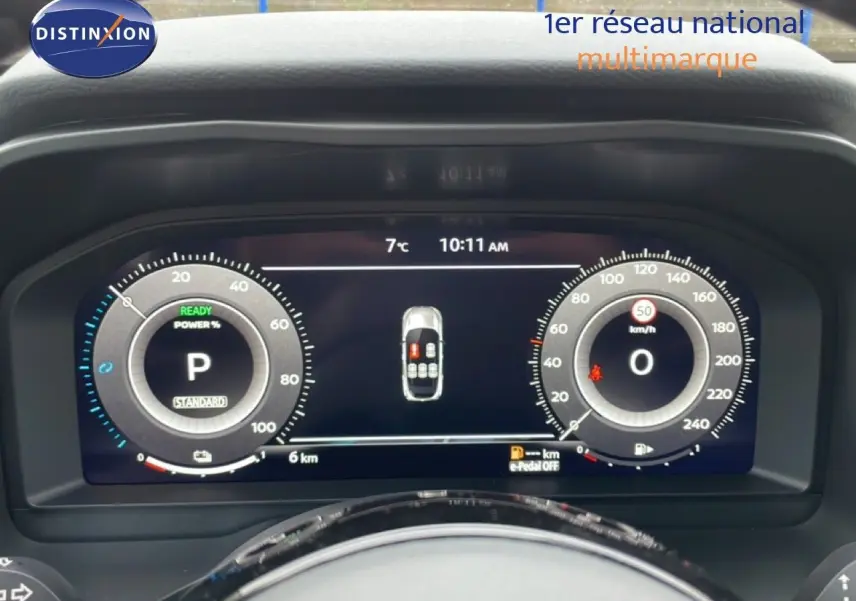 Vue rapprochée du tableau de bord numérique du Nissan Qashqai blanc nacré, affichant la vitesse et l’état du véhicule.