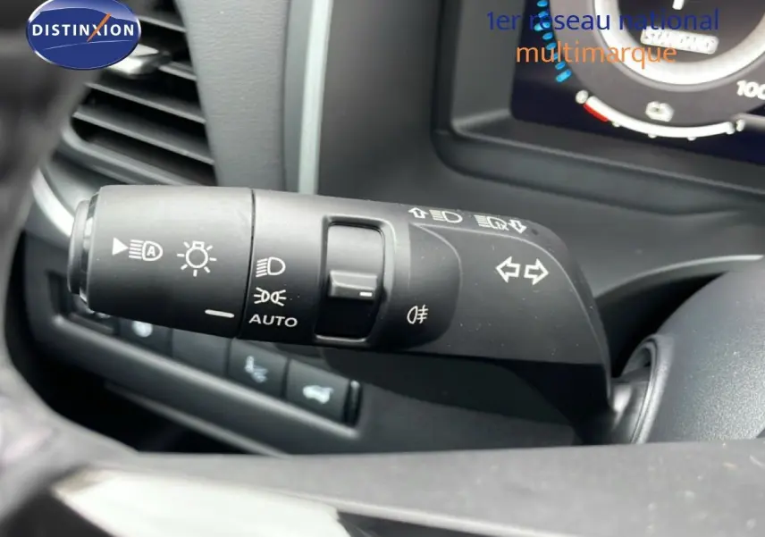 Gros plan sur la commande des phares et clignotants du Nissan Qashqai blanc nacré 2025, intérieur noir.