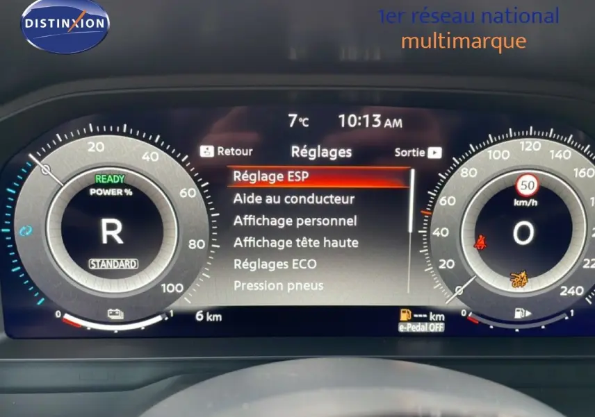Tableau de bord numérique du Nissan Qashqai blanc nacré, affichant les réglages et la vitesse à 0 km/h.