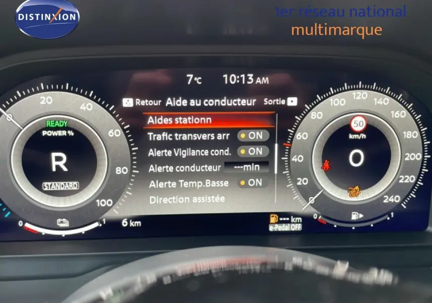 Tableau de bord numérique du Nissan Qashqai blanc nacré, affichant les aides au conducteur et la vitesse à 0 km/h.