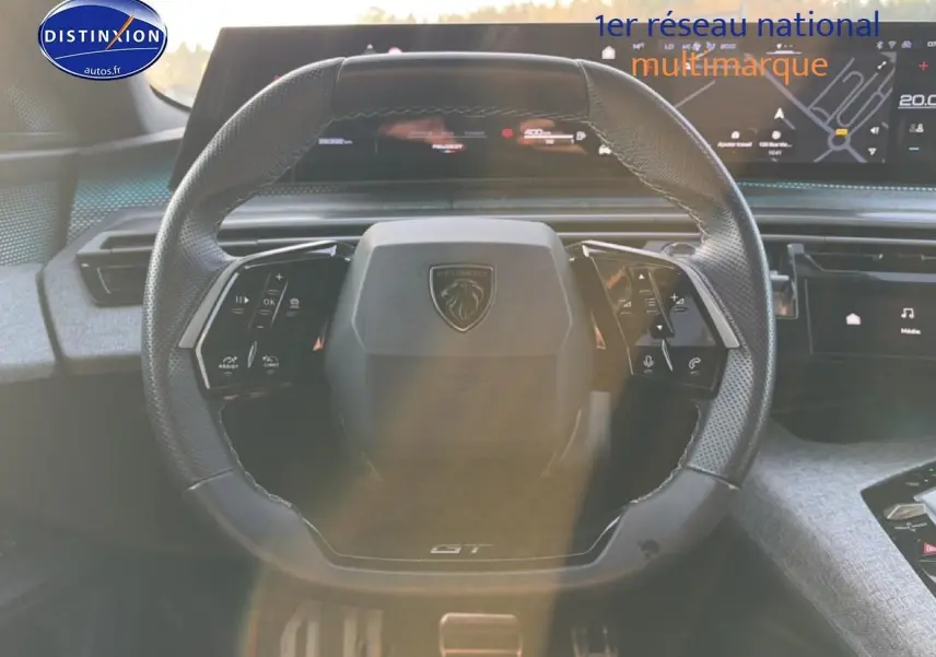 Vue rapprochée du volant cuir multifonction gris du Peugeot 3008 1.2 hybrid 145 GT avec tableau de bord numérique.