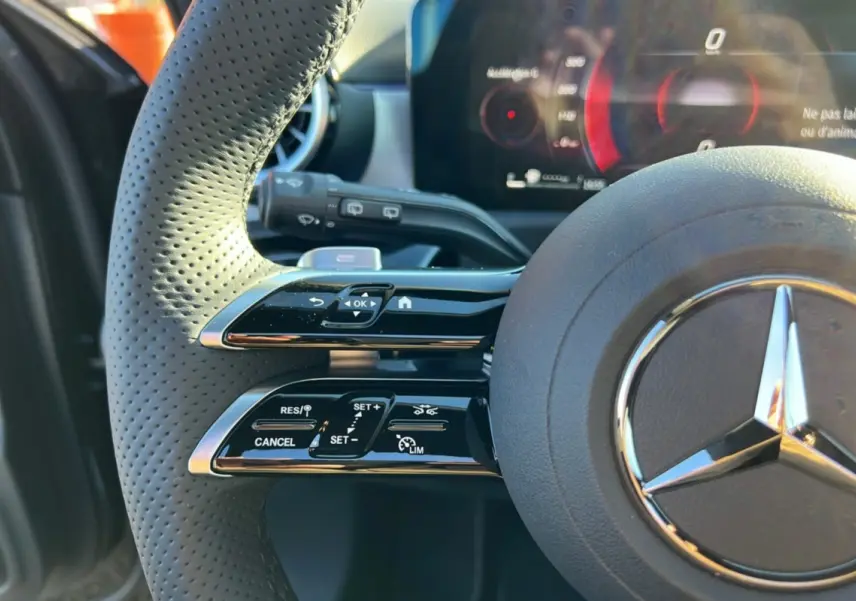 Gros plan sur le volant cuir perforé noir de la Mercedes Classe A 200D BVA Exclusive Design avec commandes multifonctions et logo étoile central.