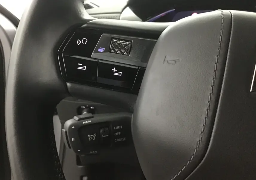 Gros plan sur la partie gauche du volant en cuir gris du DS3 Crossback E-TENSE avec commandes audio et régulateur de vitesse.