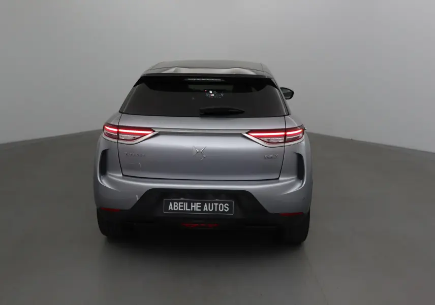Vue arrière d'une DS3 Crossback E-TENSE gris Artense avec feux LED allumés dans un studio neutre.