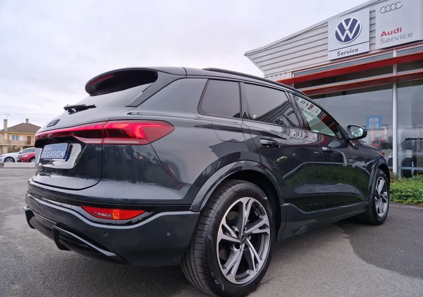 Audi Q6 e-tron Performance S-Line gris Manhattan vu en 3/4 arrière droit, avec jantes Audi Sport et détails noirs.