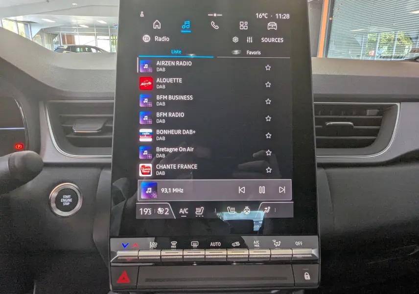Écran tactile central du tableau de bord du Renault Captur E-Tech gris Cassiopée, affichant les stations radio DAB.