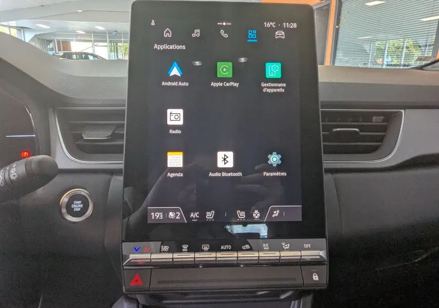 Écran tactile central du Renault Captur E-Tech 2025 affichant les applications Android Auto et Apple CarPlay, intérieur gris.