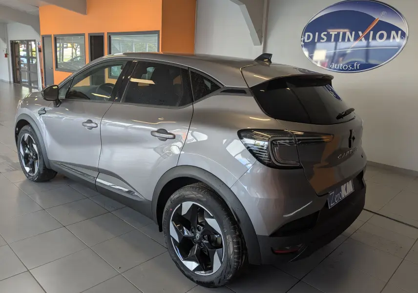 Renault Captur E-Tech gris cassiopée vu en 3/4 arrière droit, avec jantes biton et vitres teintées.