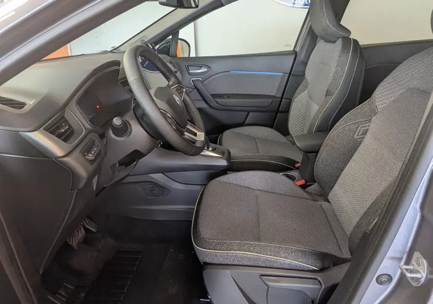 Vue intérieure côté conducteur du Renault Captur E-Tech gris Cassiopée, sièges tissu gris et volant multifonctions.