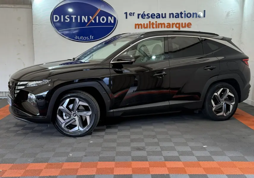 Profil droit d'un Hyundai Tucson noir 2022 avec jantes alliage modernes, stationné en intérieur showroom.