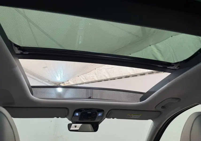 Toit ouvrant panoramique ouvert vu de l'intérieur avant du Hyundai Tucson noir 2022 avec ciel visible.