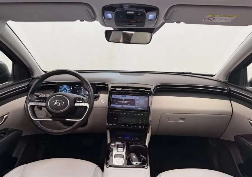 Intérieur avant du Hyundai Tucson 2022, tableau de bord beige et noir avec écran tactile central et volant multifonction.
