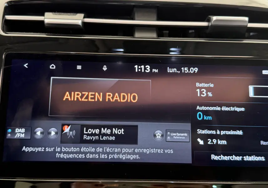 Gros plan sur l'écran tactile central du Hyundai Tucson noir, affichant la radio Airzen et l'état batterie à 13%