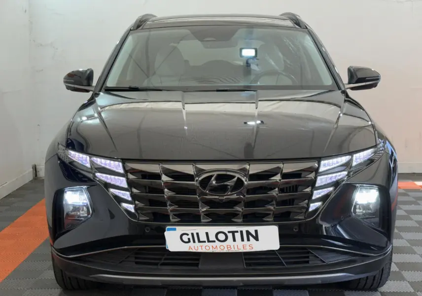 Vue frontale d'un Hyundai Tucson noir 2022 avec phares LED et calandre distinctive illuminée.