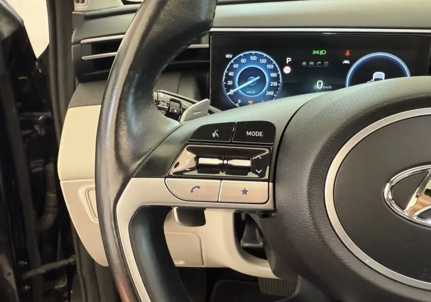 Gros plan sur le volant cuir noir et le tableau de bord digital du Hyundai Tucson 2022 hybride rechargeable.