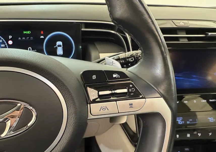 Gros plan sur le volant cuir noir du Hyundai Tucson 2022 avec commandes multifonctions et tableau de bord digital.