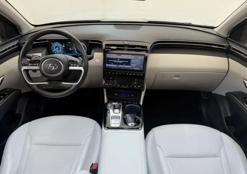 Intérieur clair du Hyundai Tucson 2022, vue frontale du tableau de bord avec écran tactile et volant multifonctions.