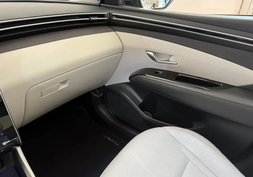 Vue intérieure côté passager avant du Hyundai Tucson 2022 noir, avec sellerie claire et tableau de bord épuré.