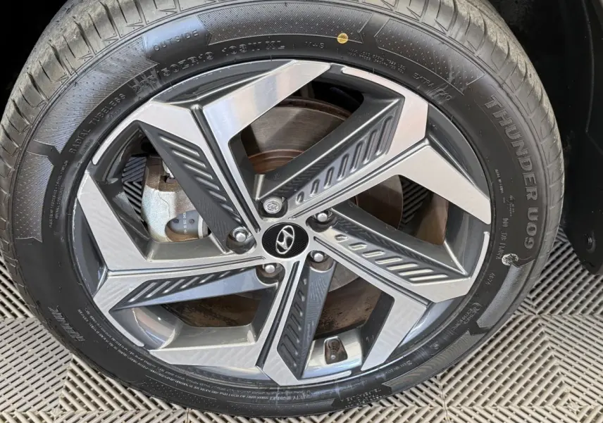 Gros plan sur la jante alliage au design géométrique du Hyundai Tucson noir 2022, avec logo Hyundai central.