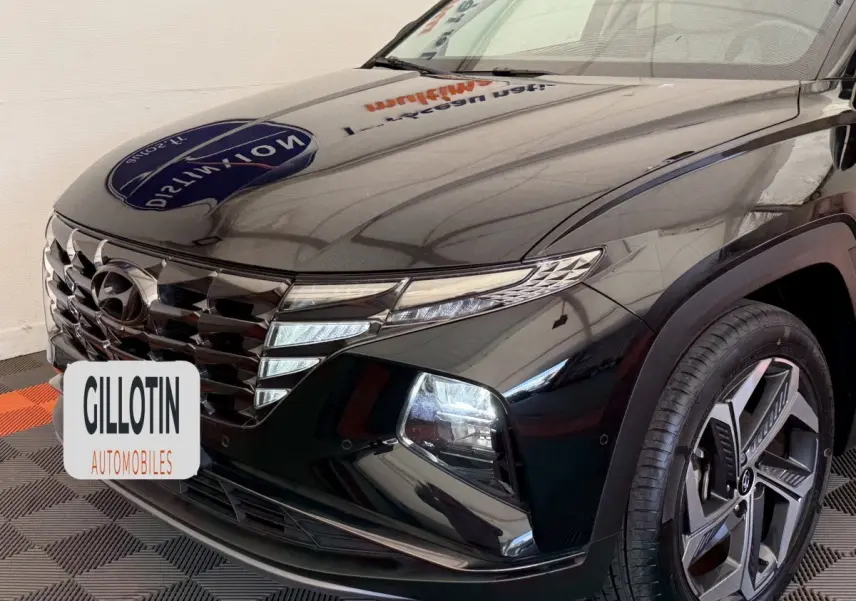 Vue 3/4 avant droit du Hyundai Tucson noir brillant avec calandre distinctive et jante alliage moderne.