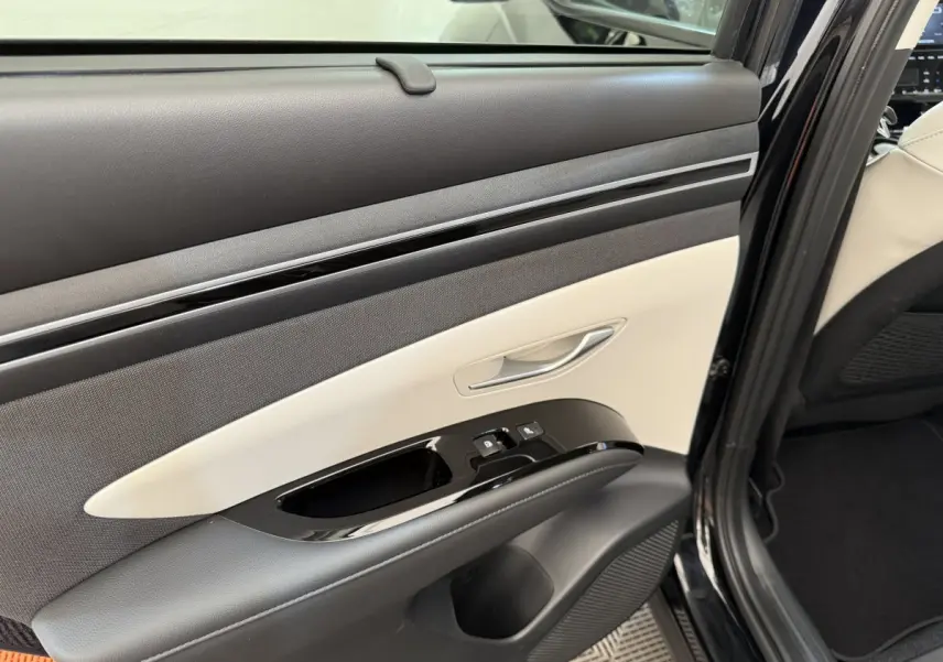 Détail de la porte arrière droite du Hyundai Tucson noir 2022 avec garniture bicolore et commandes de fenêtre.