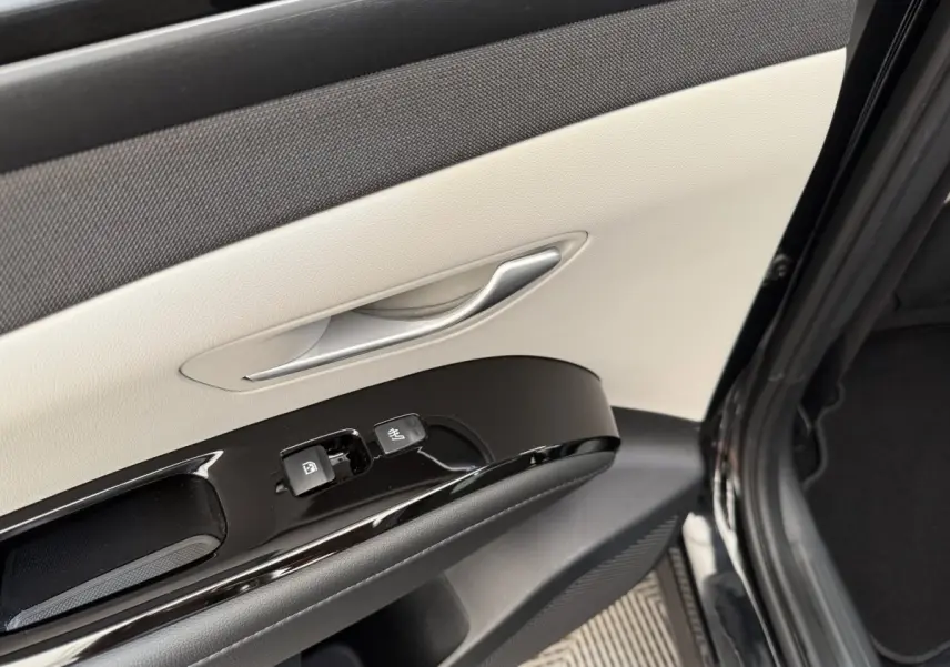 Gros plan sur la porte avant gauche noire du Hyundai Tucson 2022 avec garniture beige et commandes de vitres.