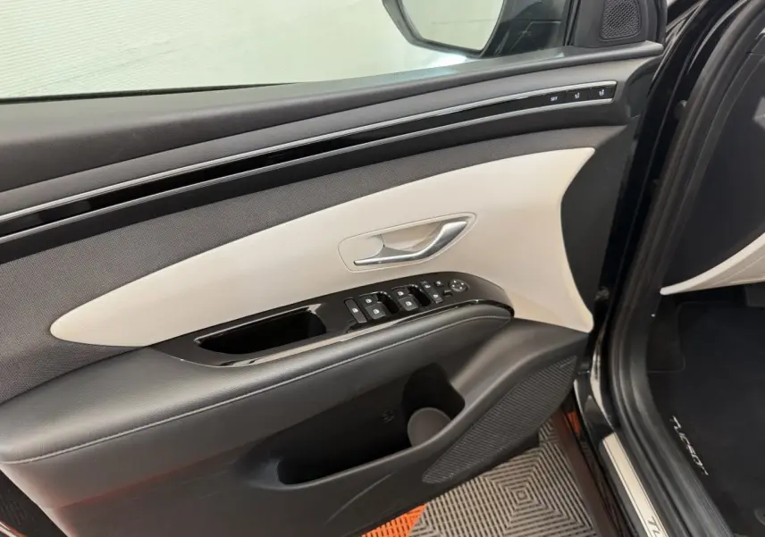 Intérieur côté gauche de la porte avant noire du Hyundai Tucson 2022 avec commandes électriques et garniture bicolore claire.