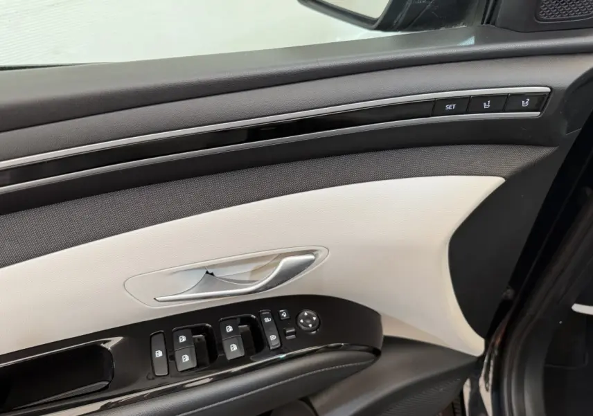 Intérieur côté conducteur du Hyundai Tucson noir 2022, panneau de porte beige et noir avec commandes électriques et réglages mémoire.
