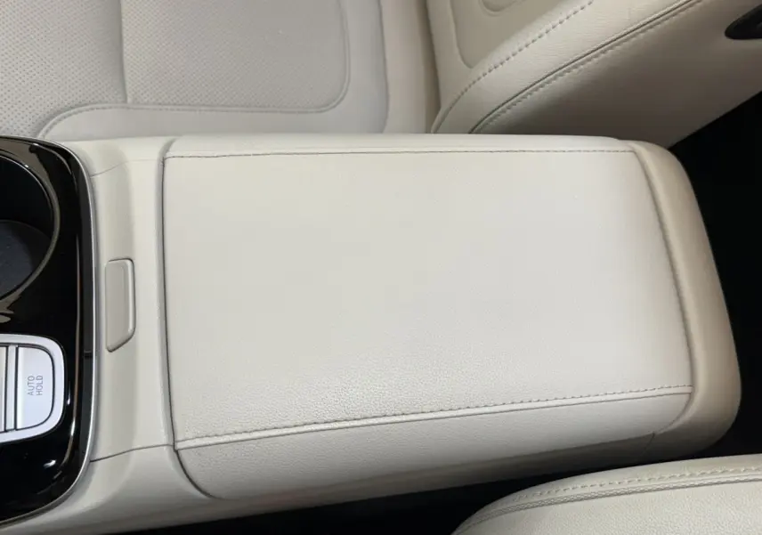 Gros plan sur l'accoudoir central beige clair du Hyundai Tucson 2022, intérieur cuir avec bouton Auto Hold visible.