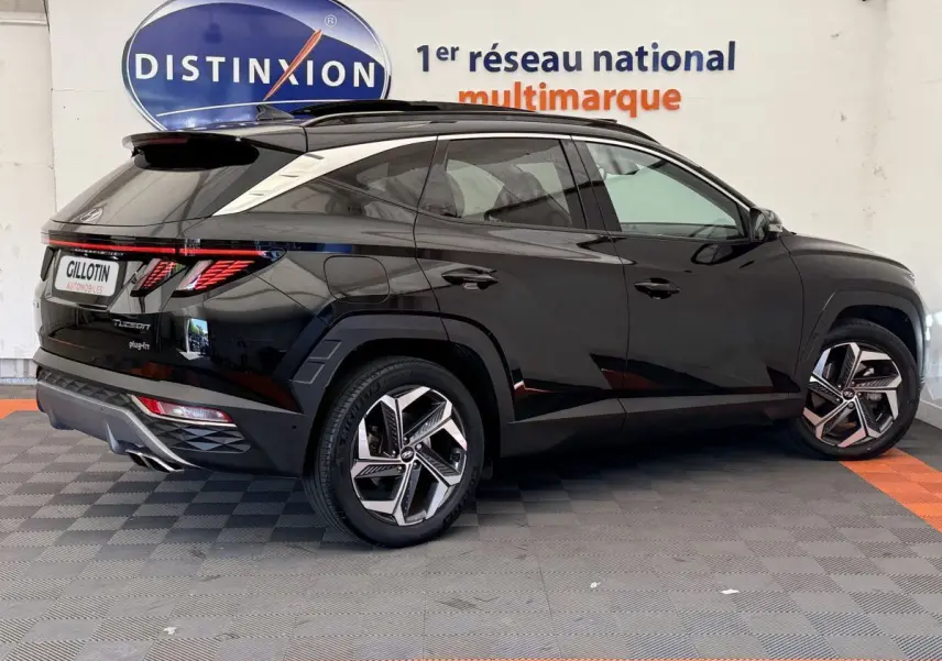 Vue 3/4 arrière côté gauche d'un Hyundai Tucson noir avec jantes alliage et feux arrière LED distinctifs.