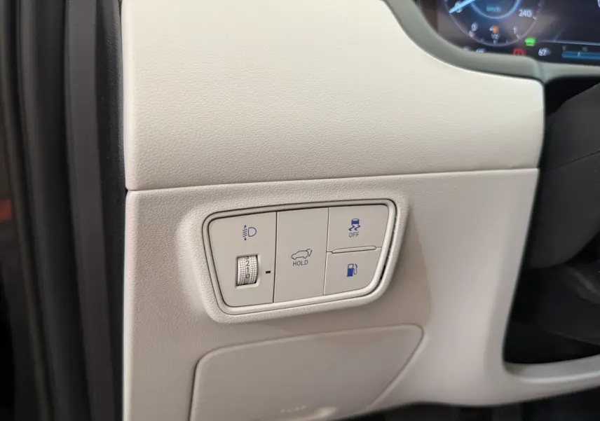 Détail du tableau de bord beige du Hyundai Tucson 2022 avec commandes d'éclairage, maintien, traction et ouverture du coffre.